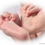 Détail de deux pieds de bébé tenus par les mains